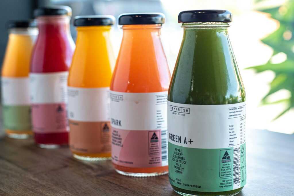 Assorted fresh bottled juices in vibrant colors on a wooden table, perfect for health enthusiasts.