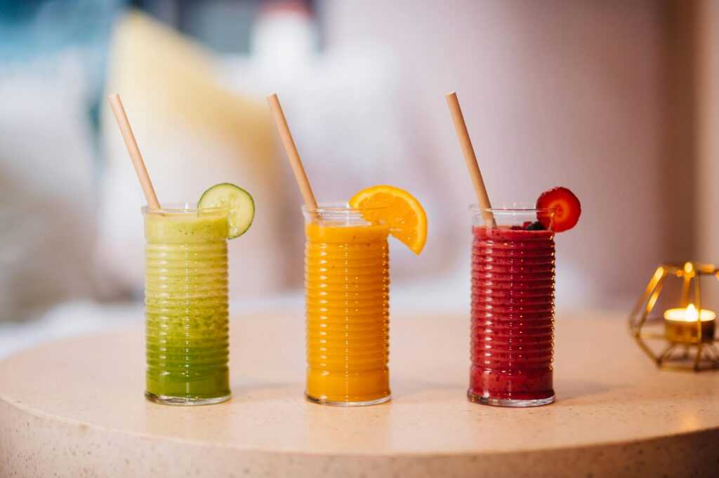 Three vibrant fruit smoothies with bamboo straws, perfect for a refreshing summer drink.
