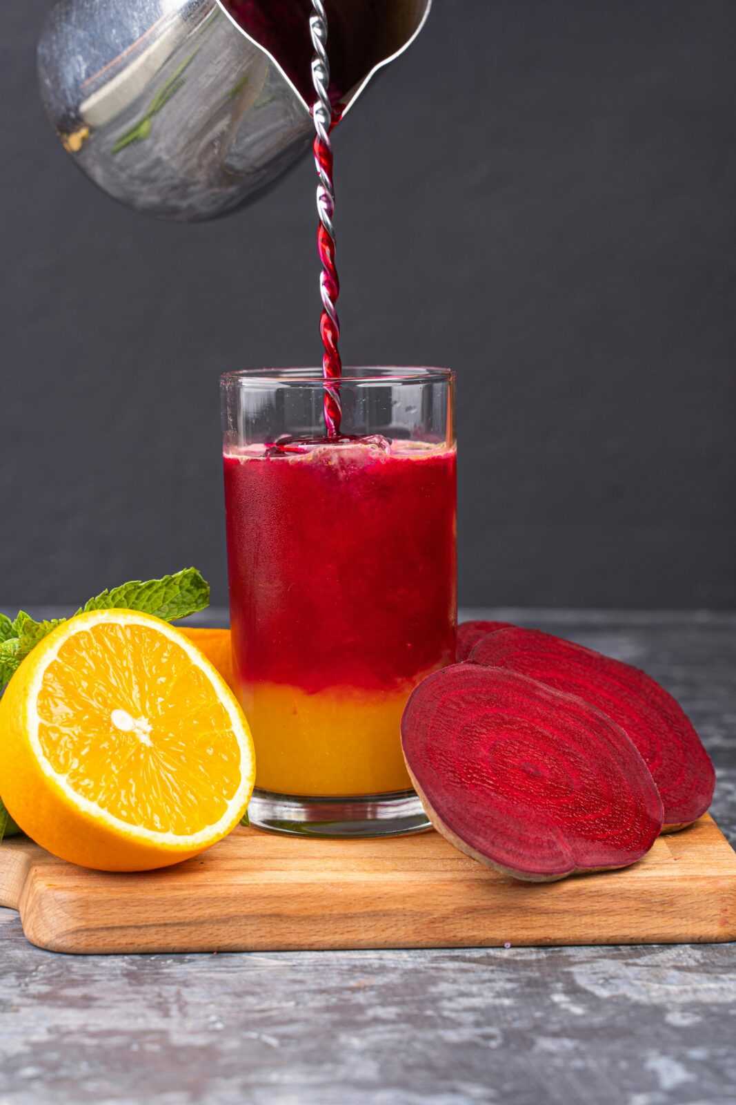 Vibrant beetroot and orange juice blend served with fresh fruit slices. Healthy and refreshing drink.