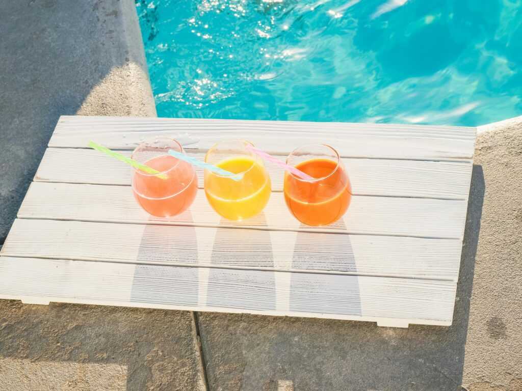 Colorful assortment of cold-pressed juices by the pool. Perfect for summer refreshment.