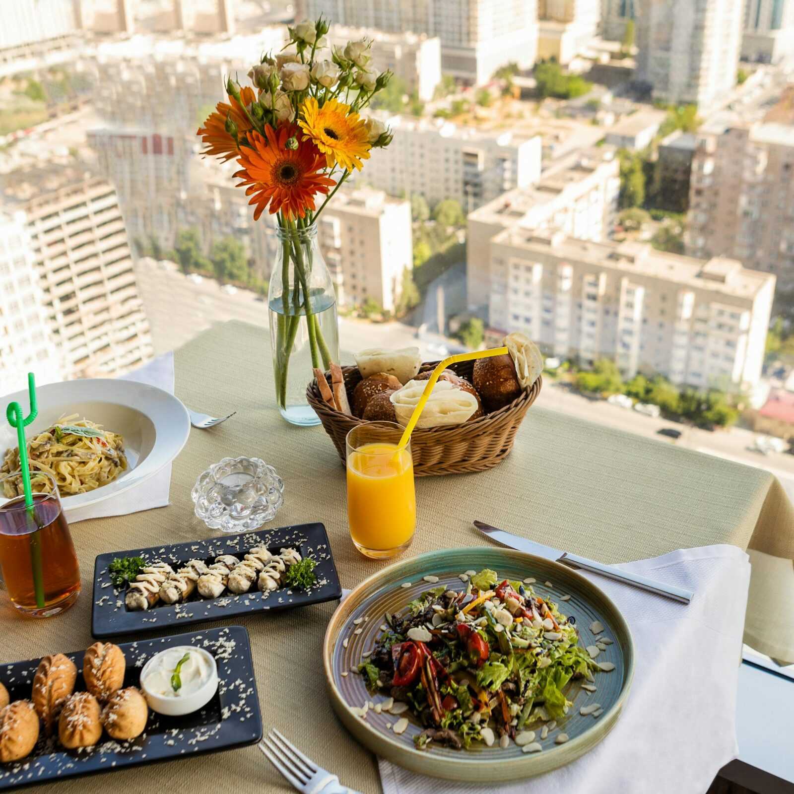 A beautifully arranged meal in a high-rise with a stunning cityscape view, offering a gourmet dining experience.